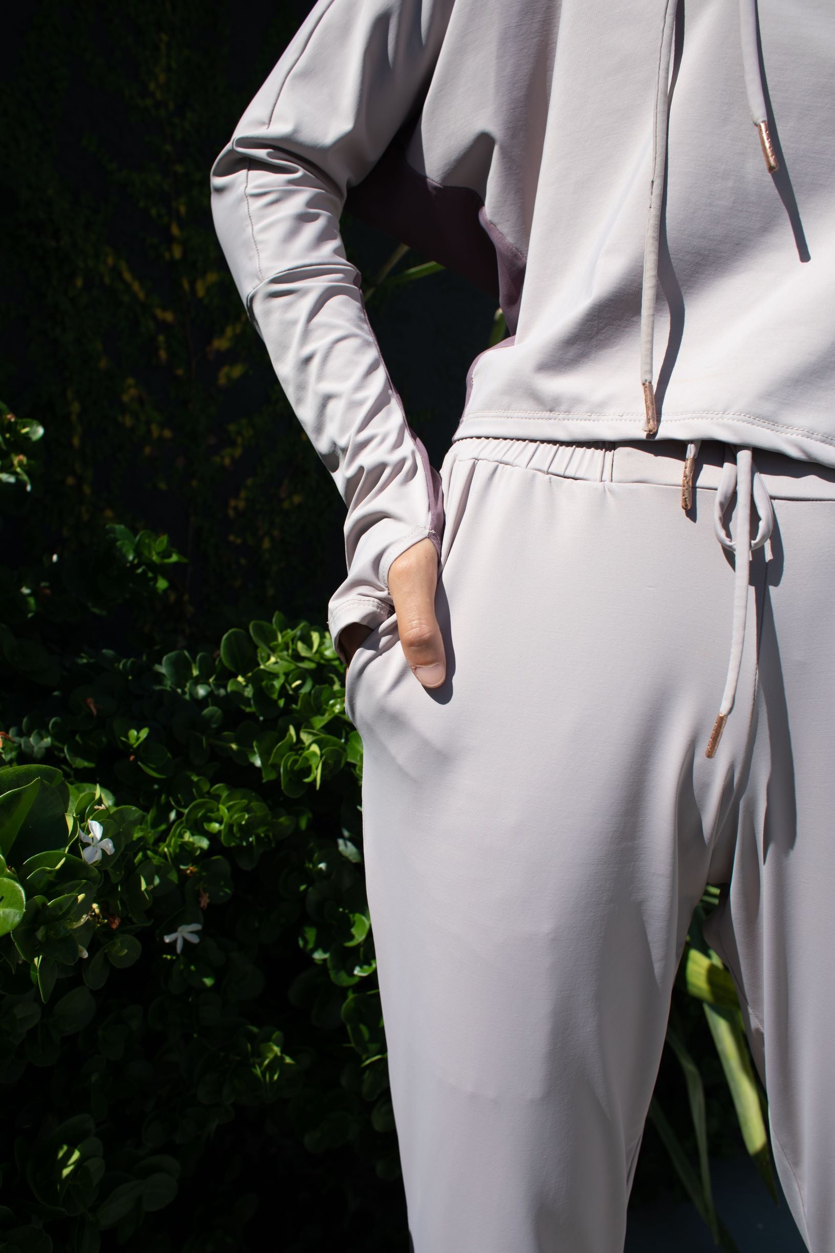 Woman wearing a soft, long sleeved sun protective hoodie with hand coverings and matching drawstring pants in iris.