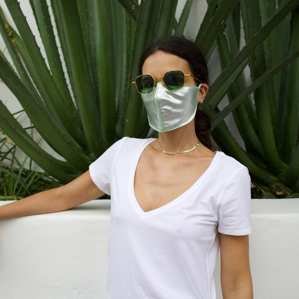 Woman in front of a cactus wearing a silver face mask.