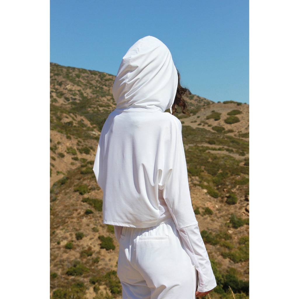 Woman outdoors wearing a lightweight, long sleeved sun protective white hoodie with hand coverings and matching UPF 50+ drawstring pants.