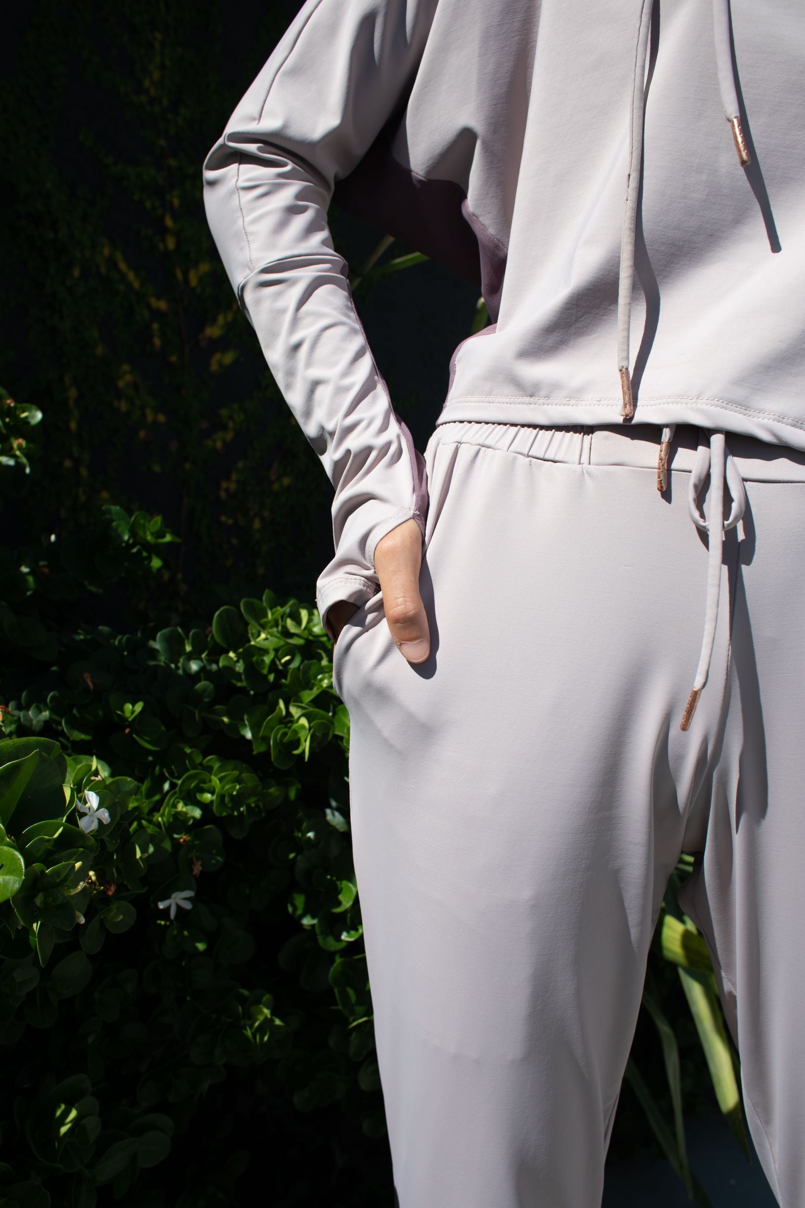 Woman wearing a soft, long sleeved sun protective hoodie with hand coverings and matching drawstring pants in iris. 