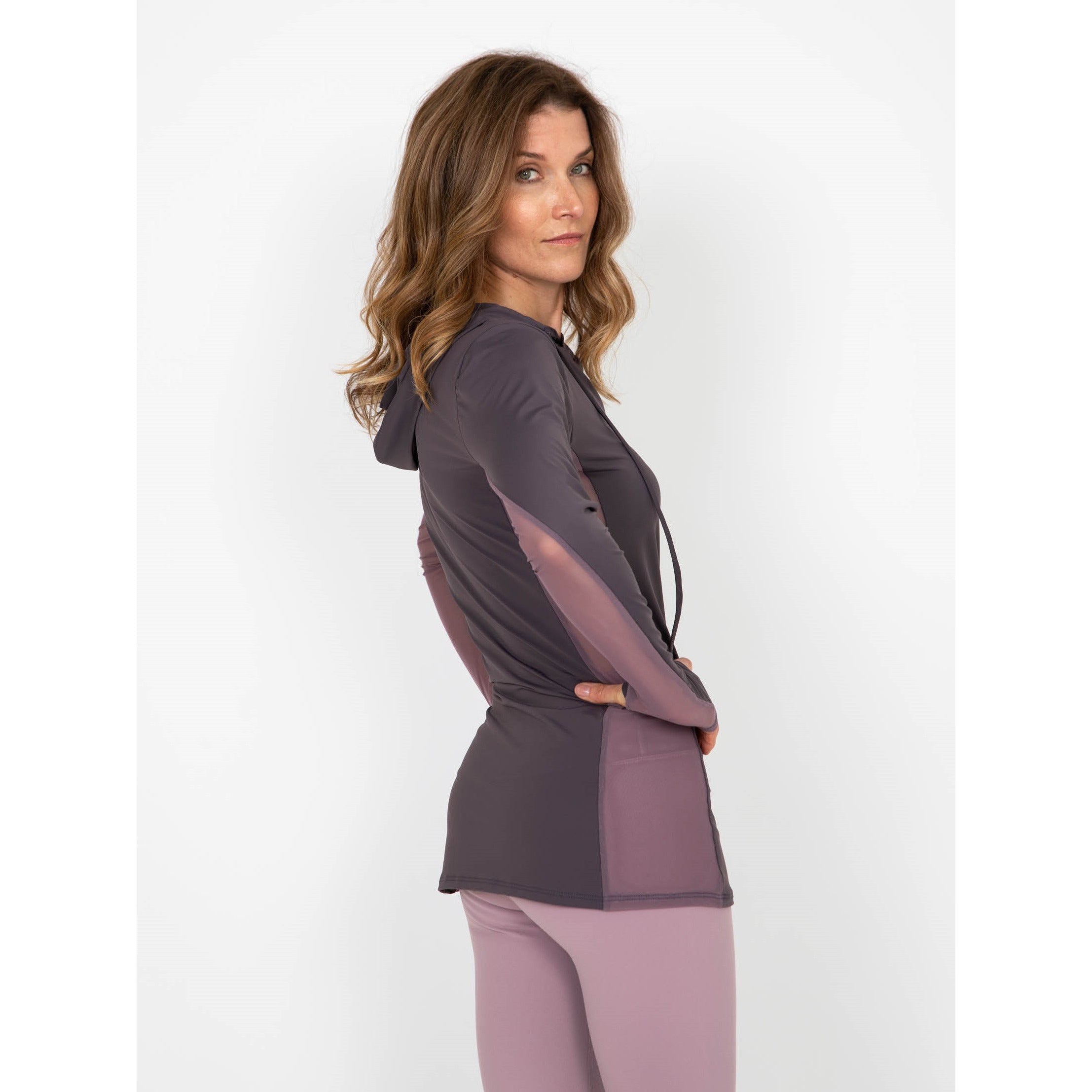 Woman wearing a long-sleeved UPF 50+ (sun protective) shirt with full hood and hand protection in plum.