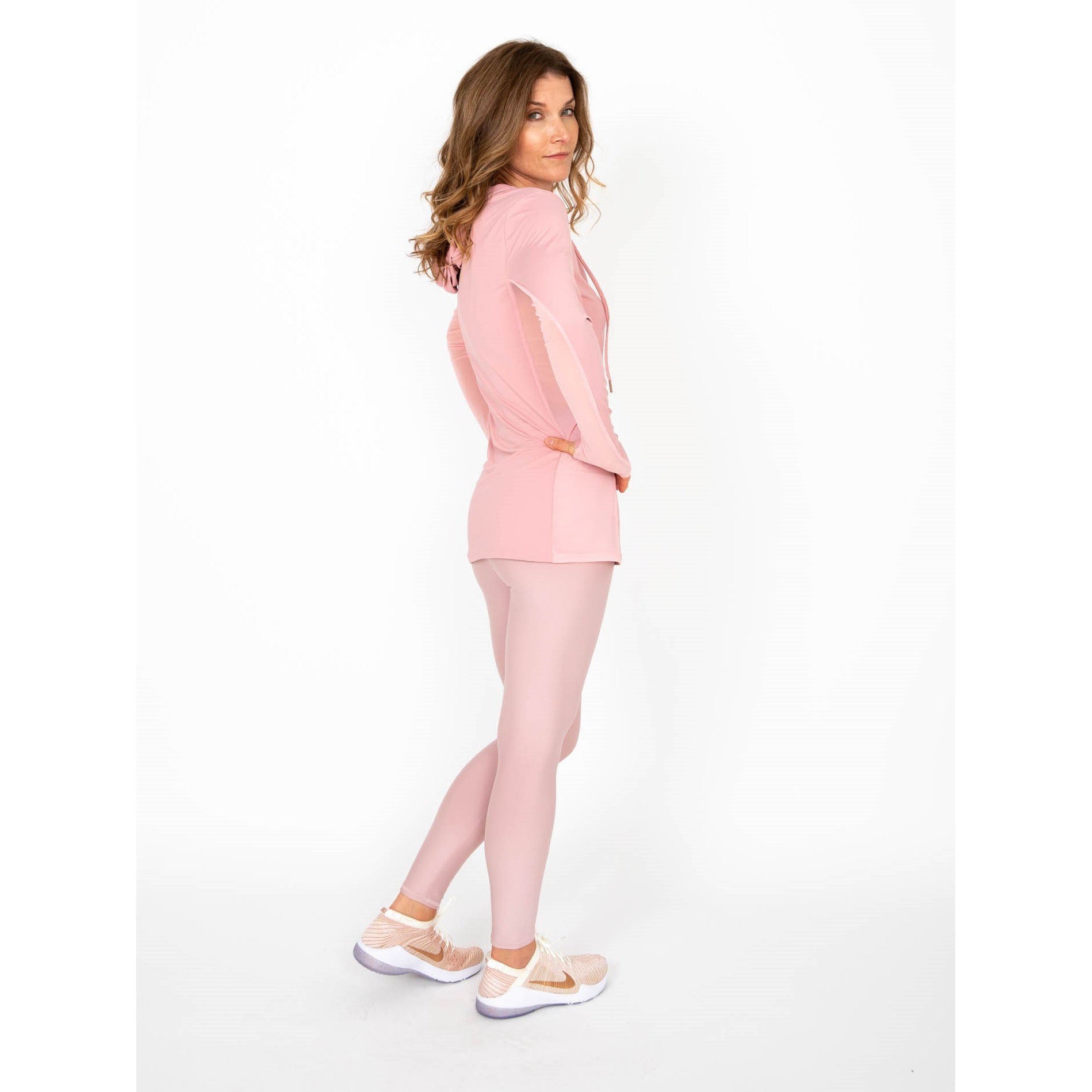 Woman wearing a long-sleeved UPF 50+ (sun protective) shirt with full hood and hand protection in pink/blush.
